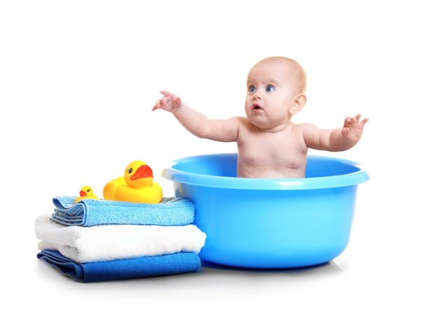 bambino fa il bagno su una bacinella blu con a fianco pila di asciugamani