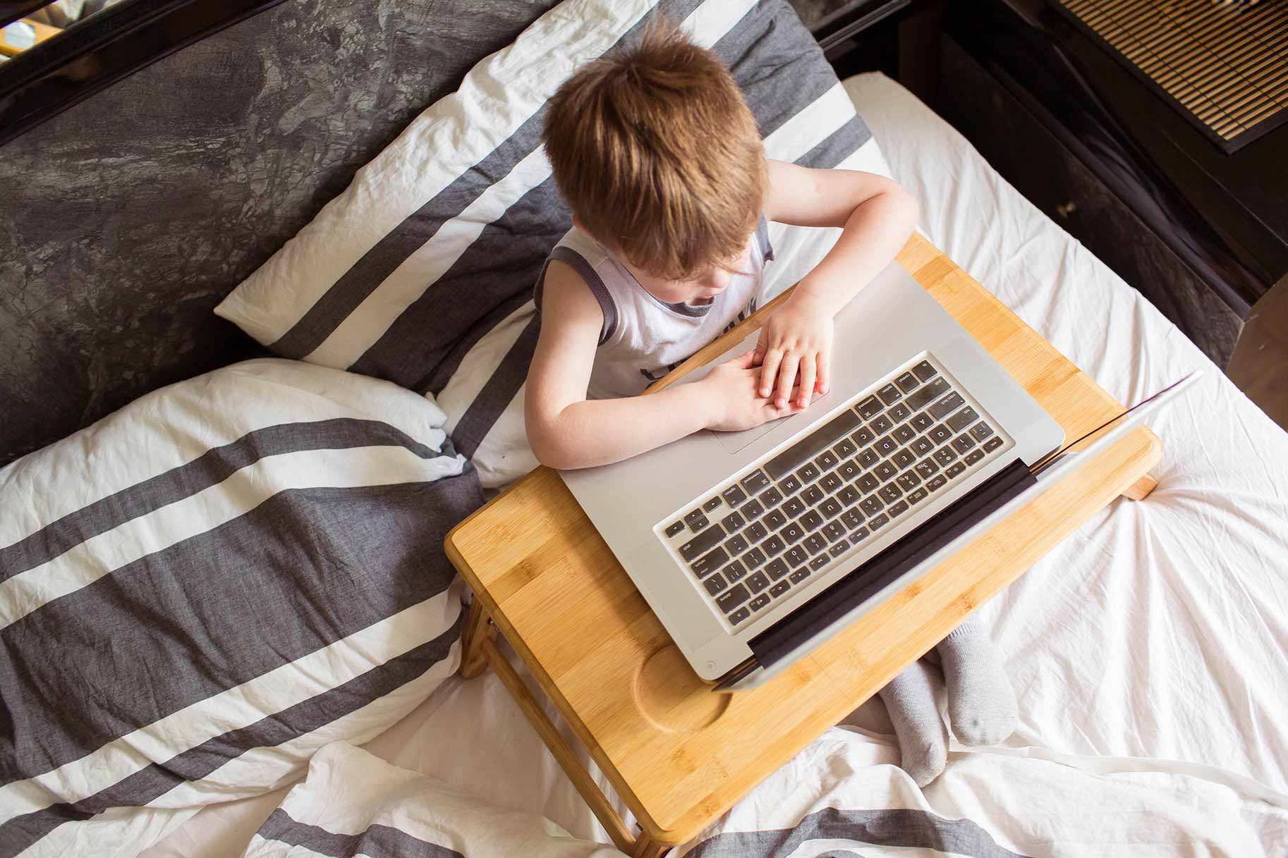 bambino sul letto con il computer