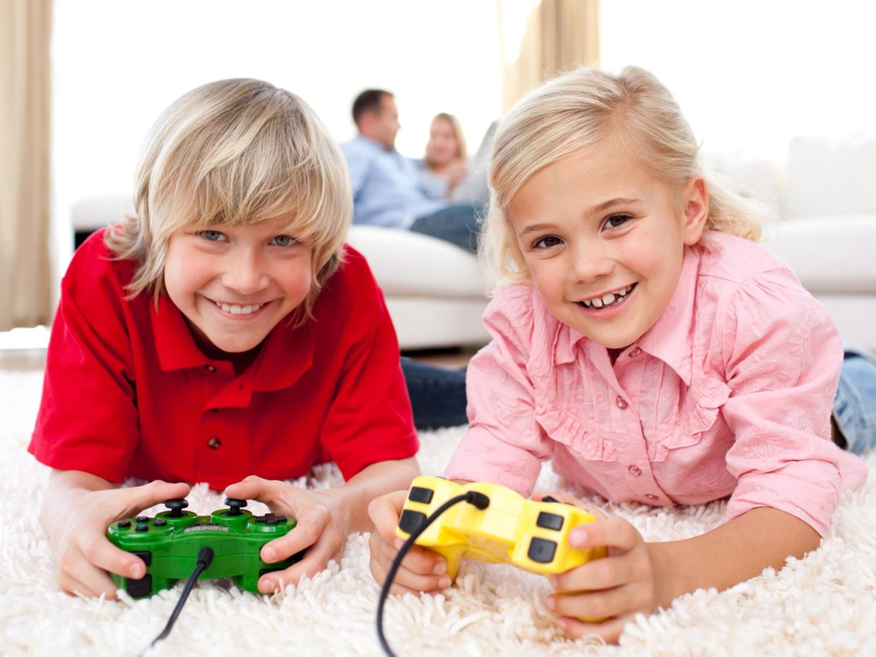 due bambini biondi sorridenti con in mano i joystick
