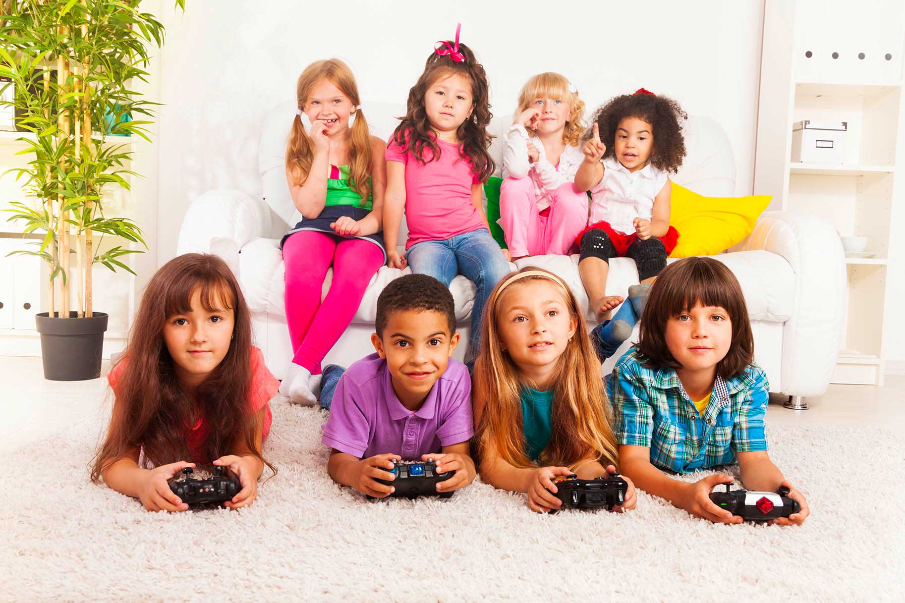 gruppo di bambini seduti sul divano giocano con i videogiochi