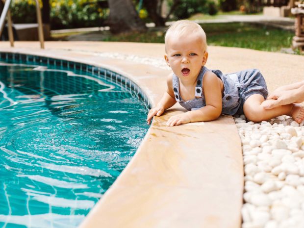 piccolo bambino gattona vicino al bordo di una piscina