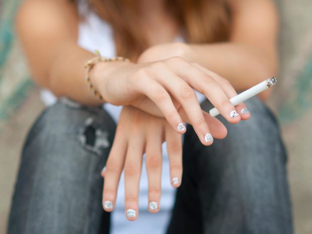 mani di ragazza adolescente che tengono in mano una sigaretta