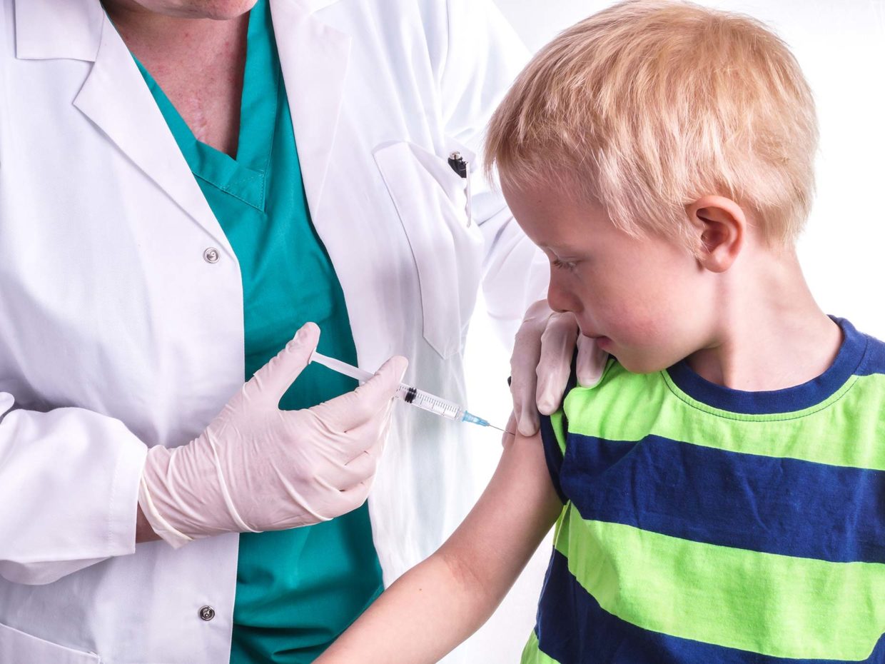 ragazzino biondo osserva l'esecuzione della sua vaccinazione