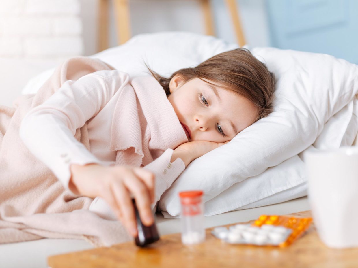 bambina malata a letto con accanto i medicinali