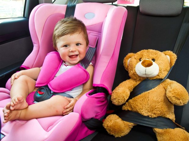 bambino felice sul seggiolino auto con il suo orsacchiotto di peluche