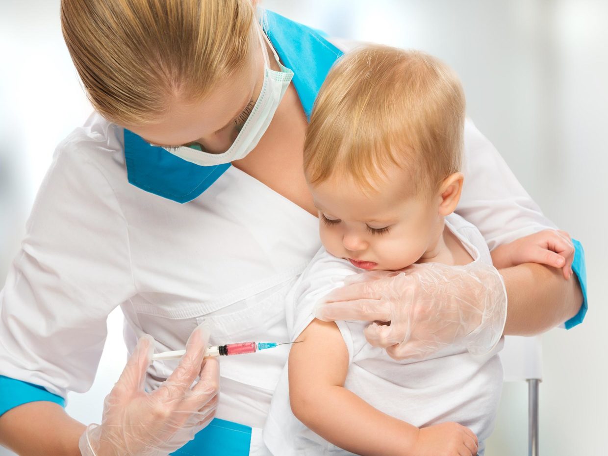 bambino tenuto ferma dal pediatra mentre somministra il vaccino