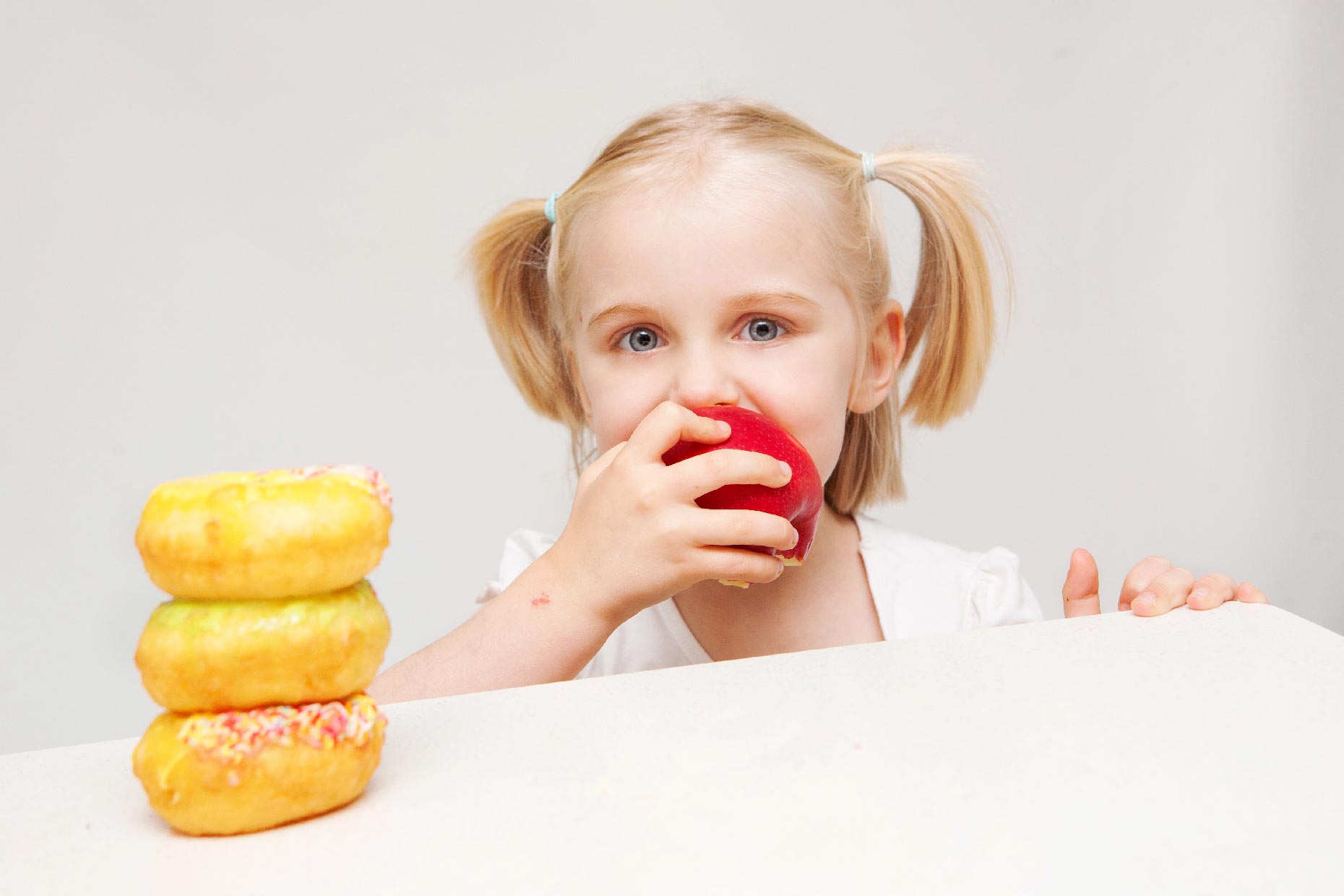 bambina mangia una mela e non le ciambelle