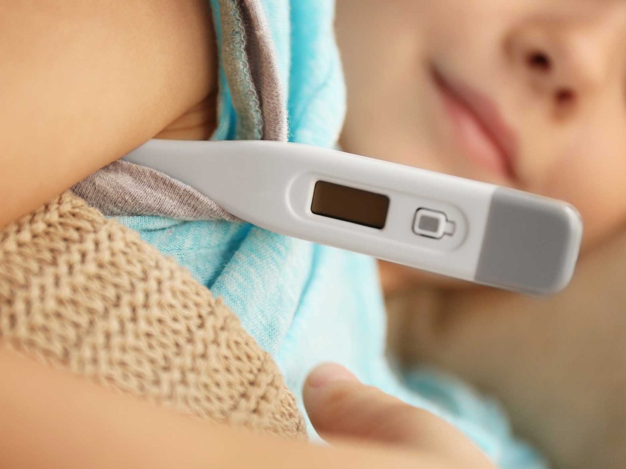 bambino a letto misura la temperatura con termometro elettronico