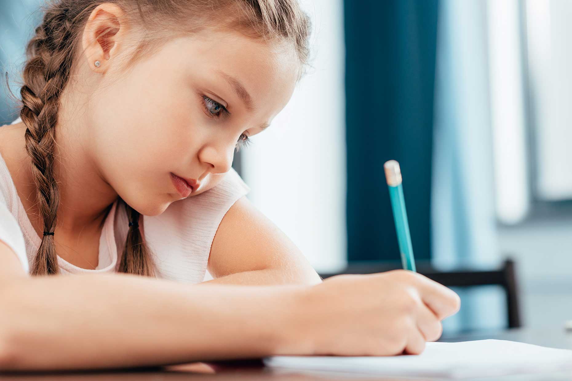 bambina con le trecce concentrata scrive con la matita