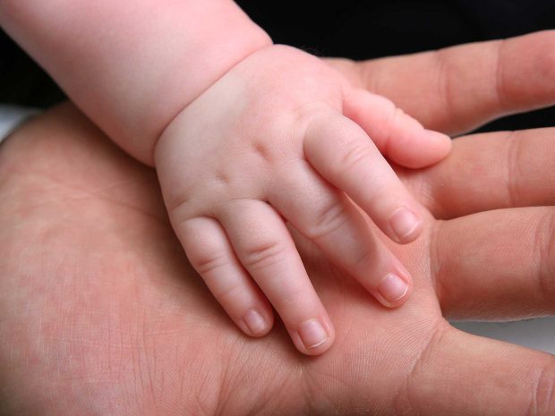 mano di neonato che tocca mano di un adulto