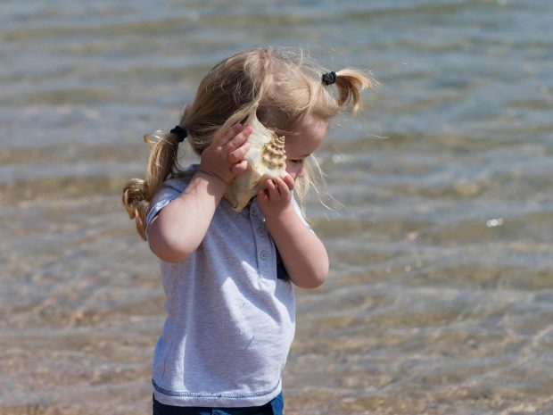 bambina al mare ascolta i suoni prodotti da una conchiglia di mare