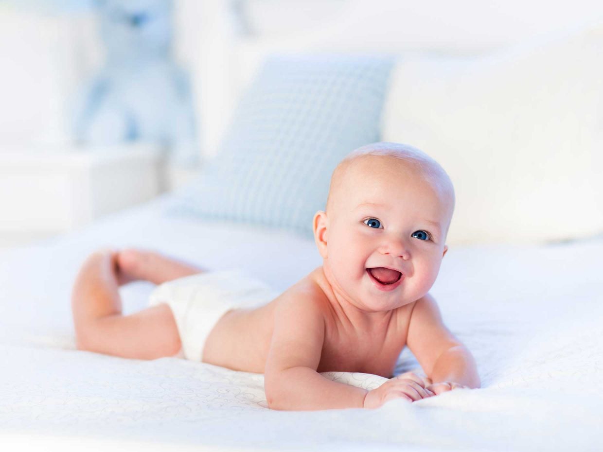 neonato sorridente disteso in posizione prona