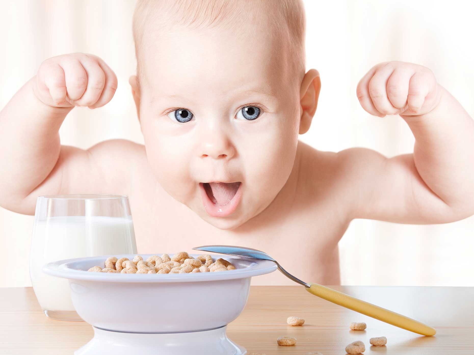 bambino esulta davanti una ciotola di cereali e un bicchiere di latte