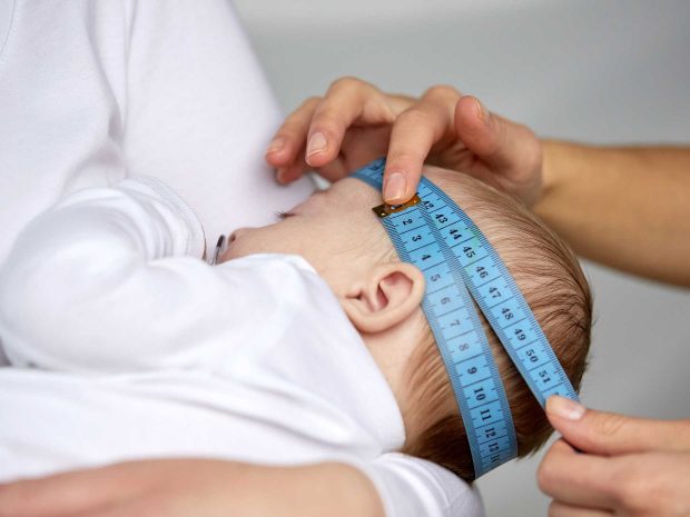 adulto misura il cranio del neonato con un metro azzurro