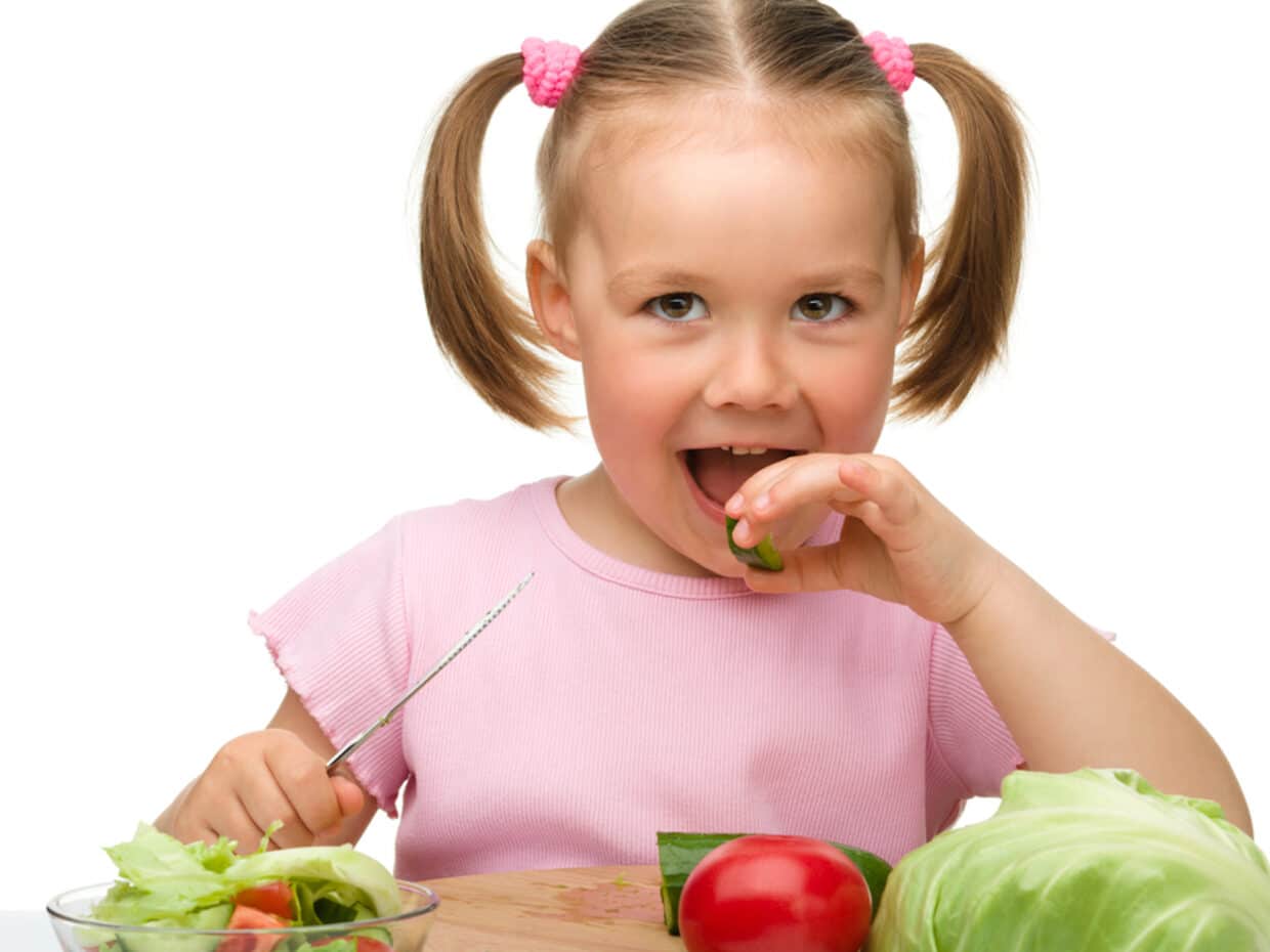 Bambina che mangia verdure: concetto di fibre alimentari